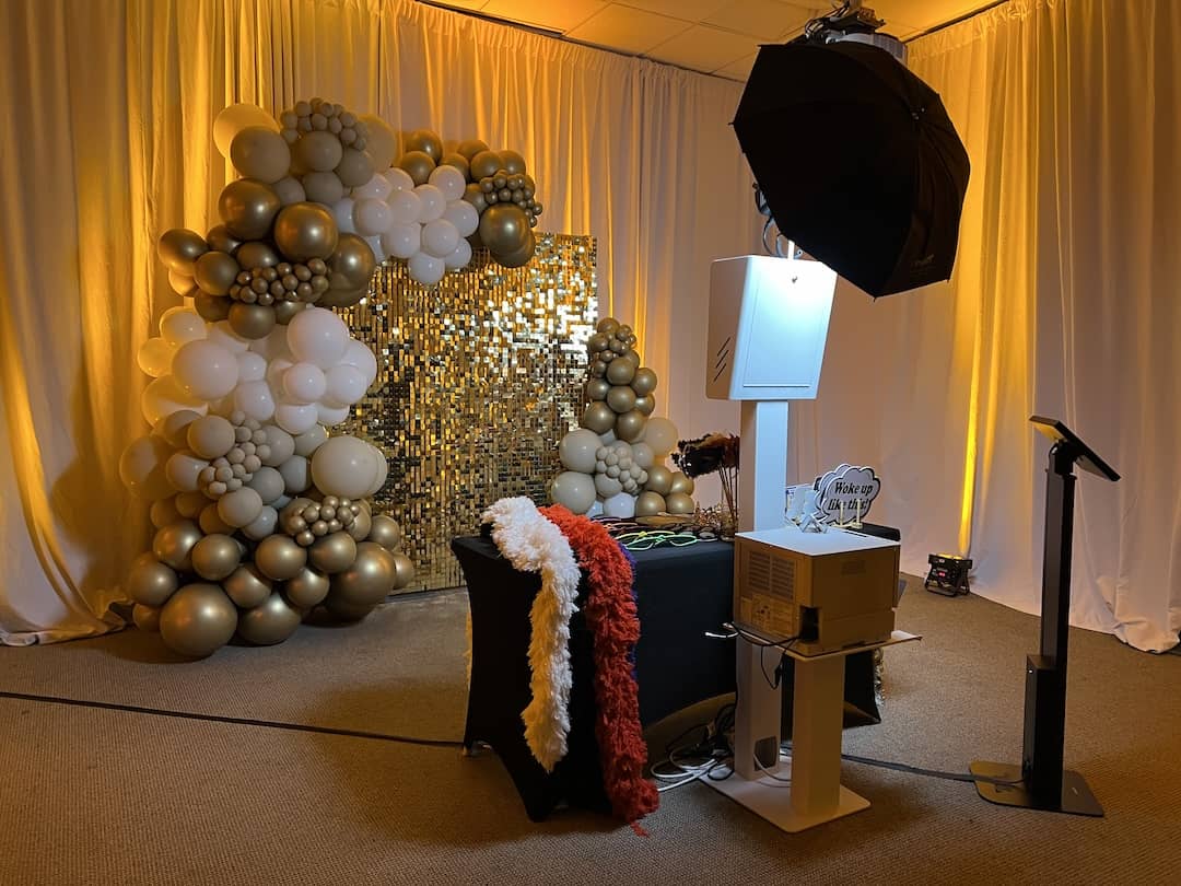 MN Booth Modern Photo Booth set up with studio lighting, a gold sequin backdrop, and balloon decor
